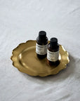 Brass Ruffle Edge Tray with two bottles on a soft surface, showcasing its vintage-inspired design.